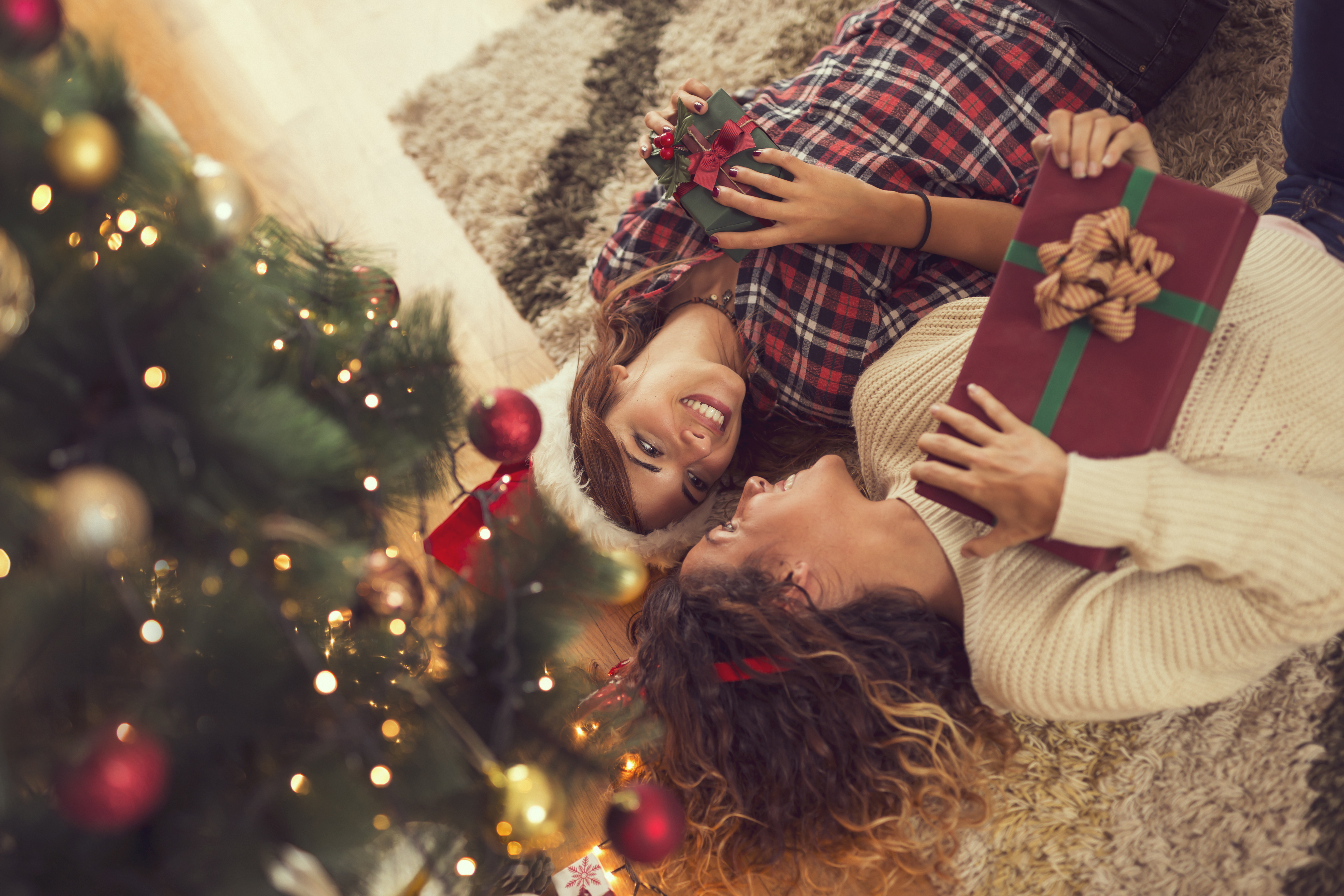 two people holding gifts under tree